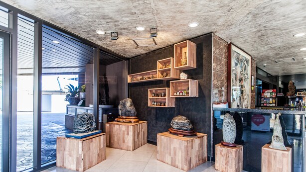 A modern interior with wooden display shelves, a large window, and a concrete ceiling. - Cheonjiyeon Hotel (Seogwipo)
