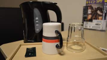 A coffee maker, a mug, and a glass on a tray.
