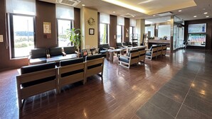 A spacious lobby with wooden flooring, seating areas, and large windows.