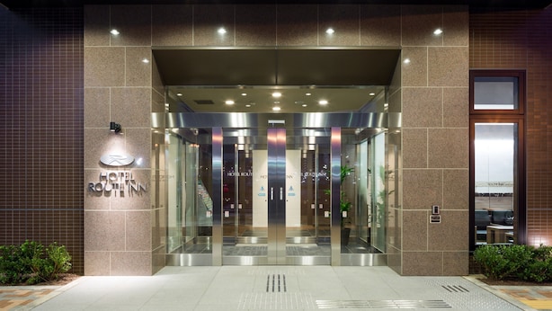 A hotel entrance with a modern design, featuring a glass door and a sign that reads "HOTEL ROUTINN".
