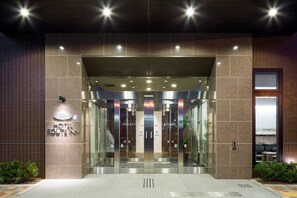 A hotel entrance with a modern design, featuring a glass door and a sign that reads "HOTEL ROUTINN". - Hotel Route - Inn Ebina Ekimae (Ebina)