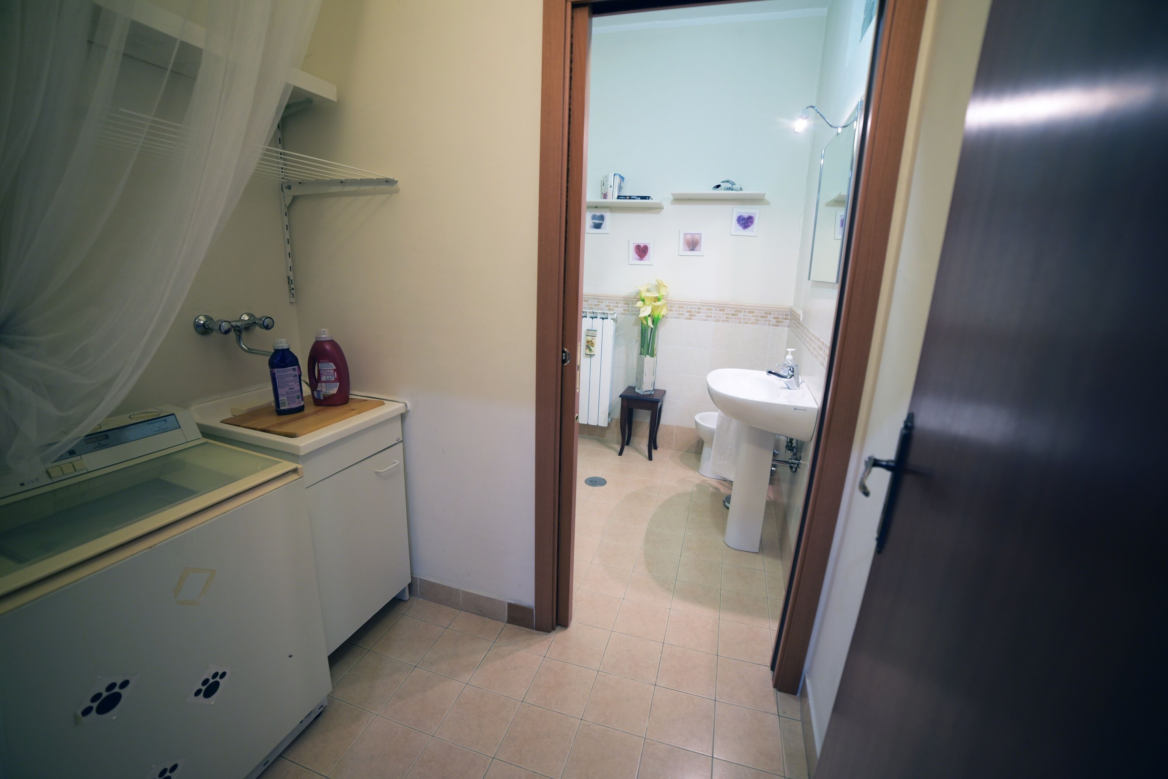 A bathroom with a white sink, a mirror, and a shower area. There are toiletries on the counter and a towel rack above the sink.