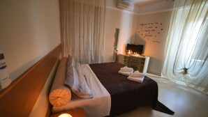 Een hotelkamer met een bed, nachtkastje met een kaars, een spiegel en een wand met een decoratief citaat.