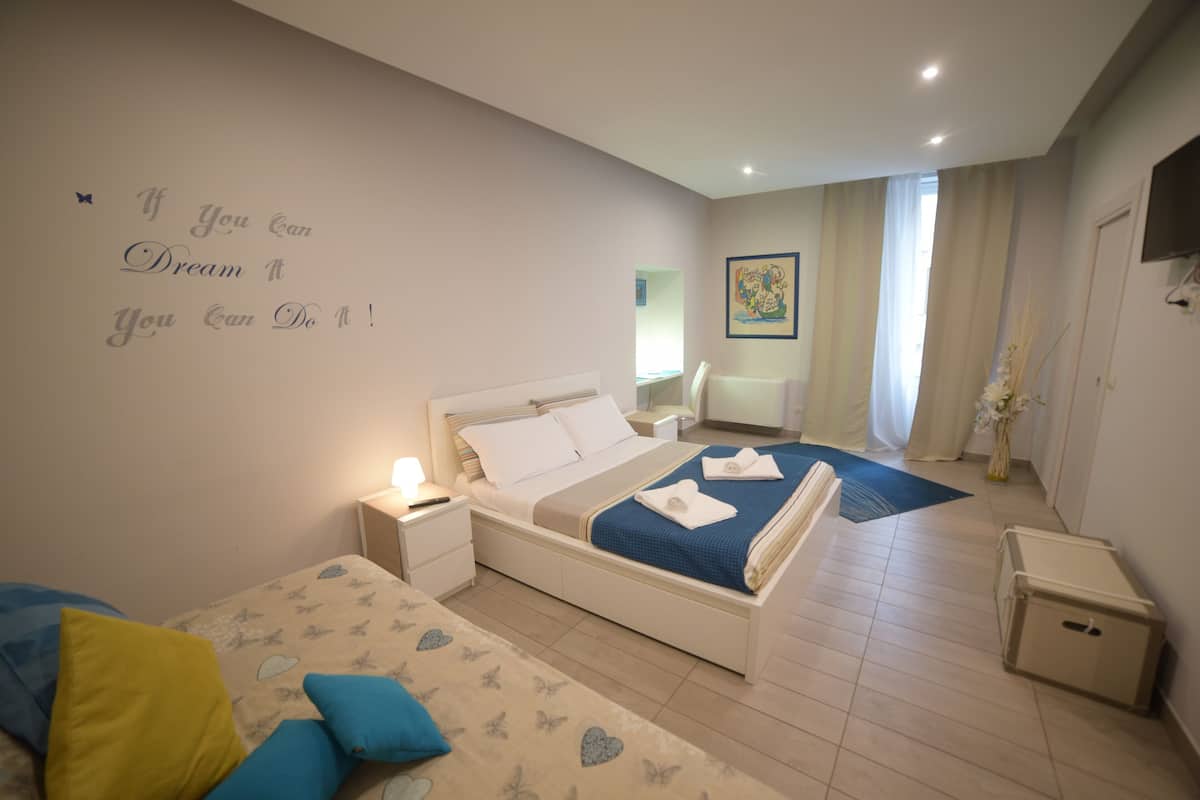 A hotel room with two beds, a wall with motivational quote, a painting, and a TV on the wall.