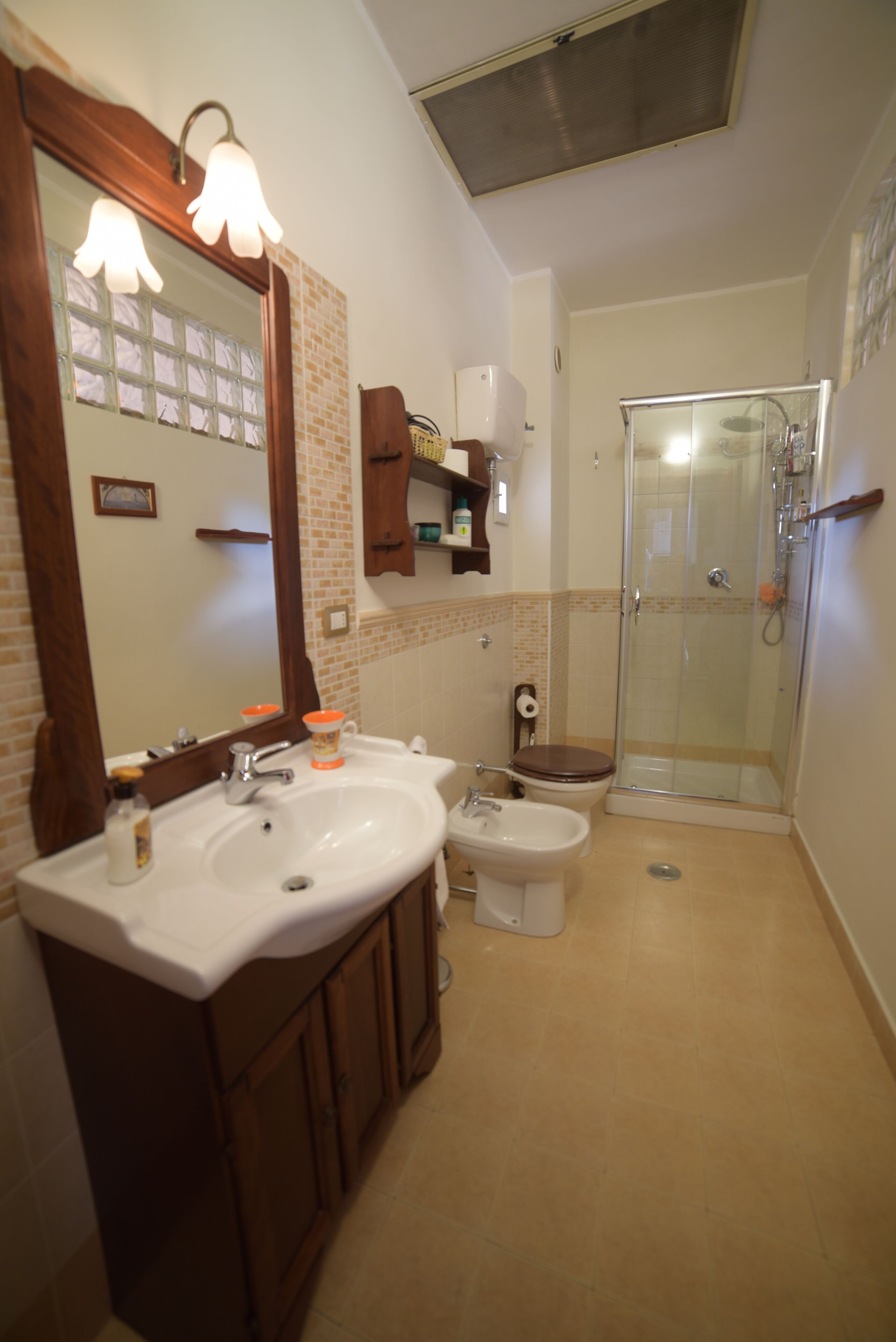 Un baño con un espejo grande, dos lavamanos, un inodoro y una ducha con mampara de vidrio.