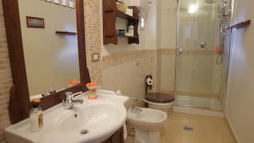 Une salle de bain dotée d’un grand miroir, de deux lavabos, de toilettes et d’une douche à parois de verre.