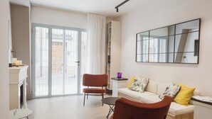 Een moderne woonkamer met een bank, fauteuils, een salontafel en een grote spiegel.