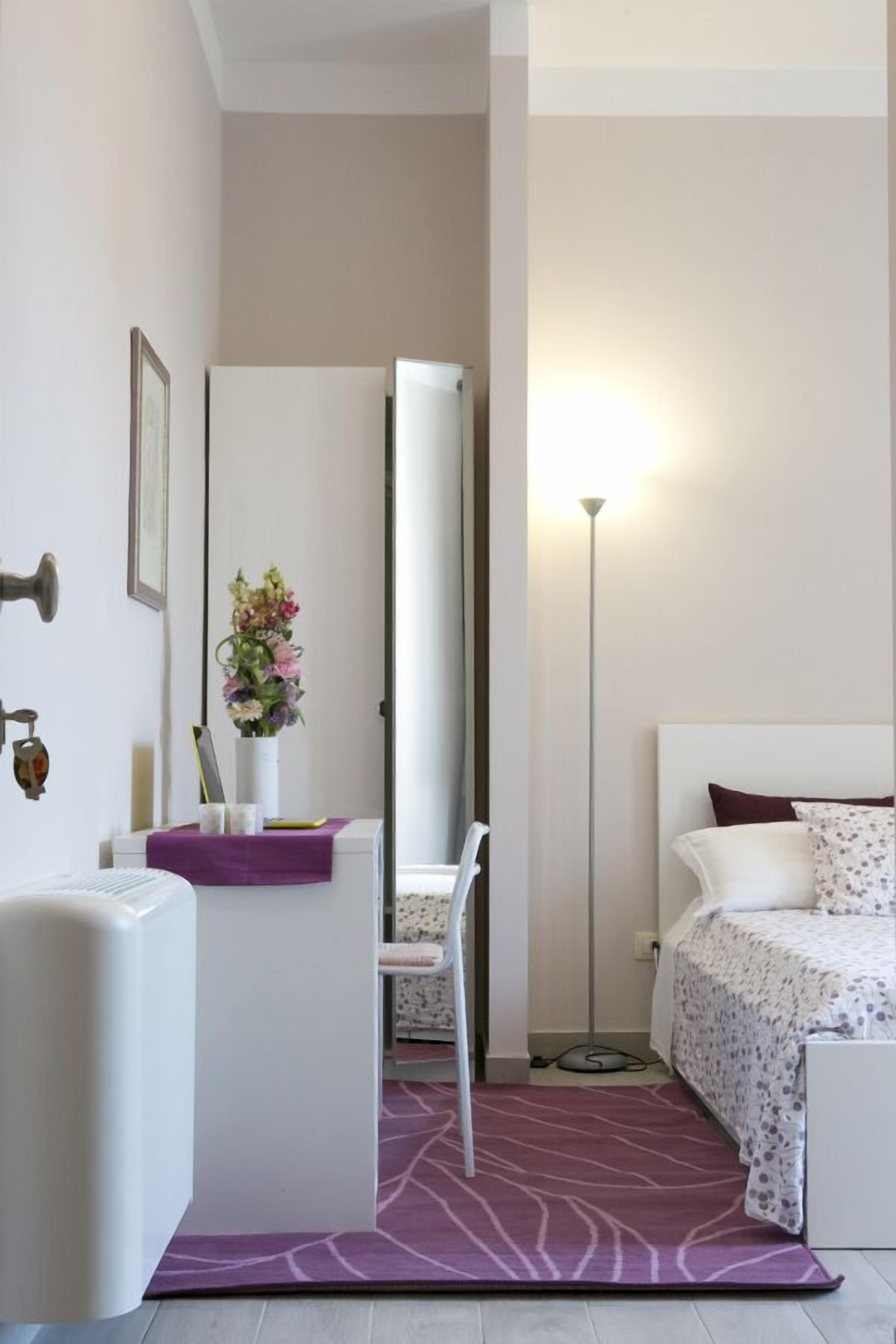 Ein modernes Schlafzimmer mit Bett, Nachttisch, Stuhl und Schreibtisch.