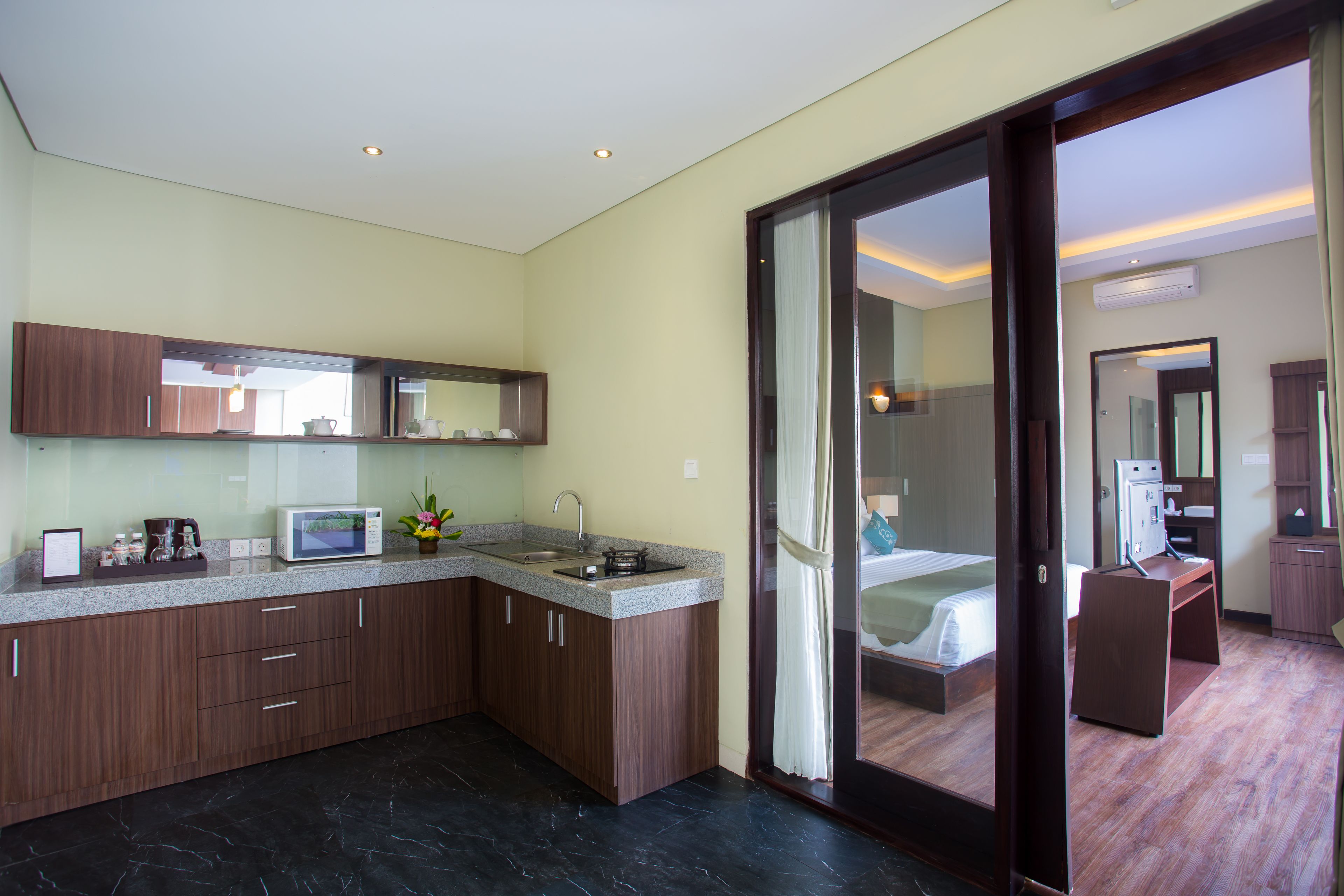 A modern hotel room with a kitchen area, a large bed, and a separate desk area.