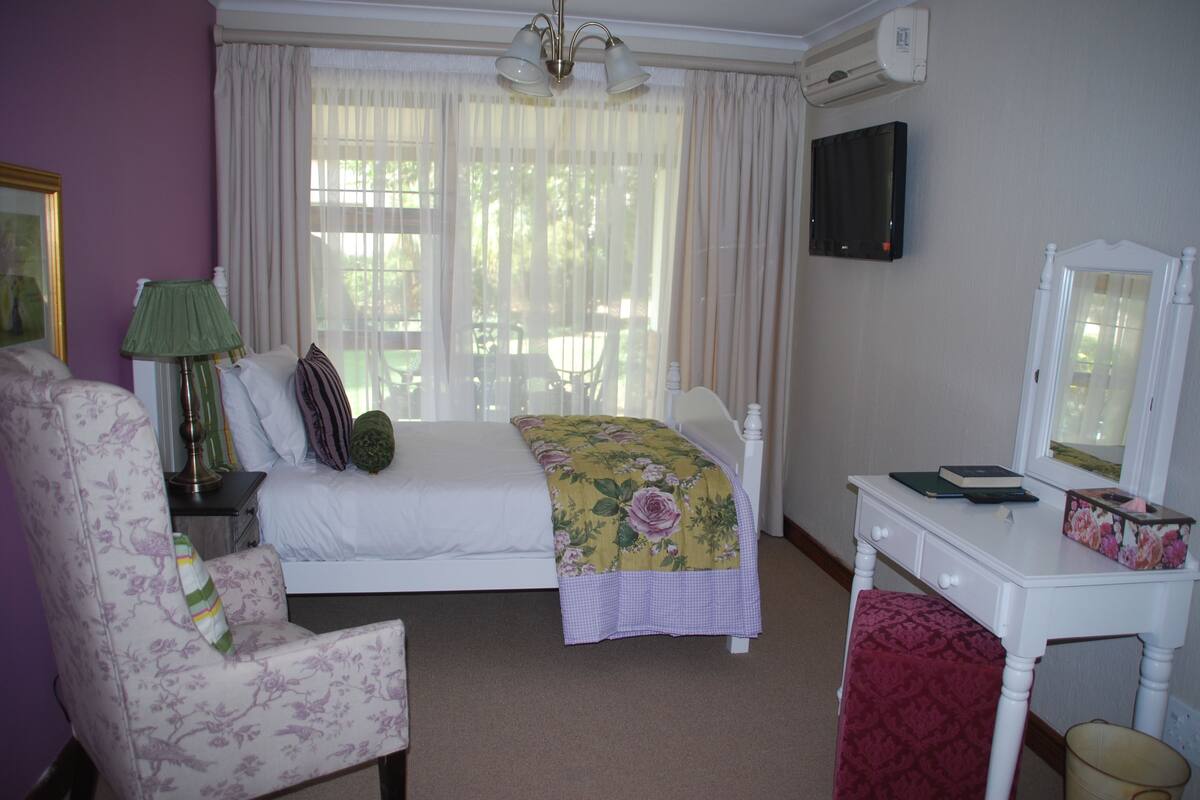 A bedroom with a bed, a chair, a desk, and a television.