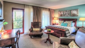 A hotel room with a bed, a desk, a chair, a small table, and a balcony with curtains. - Sunninghill Guest Lodge (Sandton)