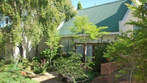 A garden with a house, a stone pathway, and a variety of plants. - Sunninghill Guest Lodge (Sandton)
