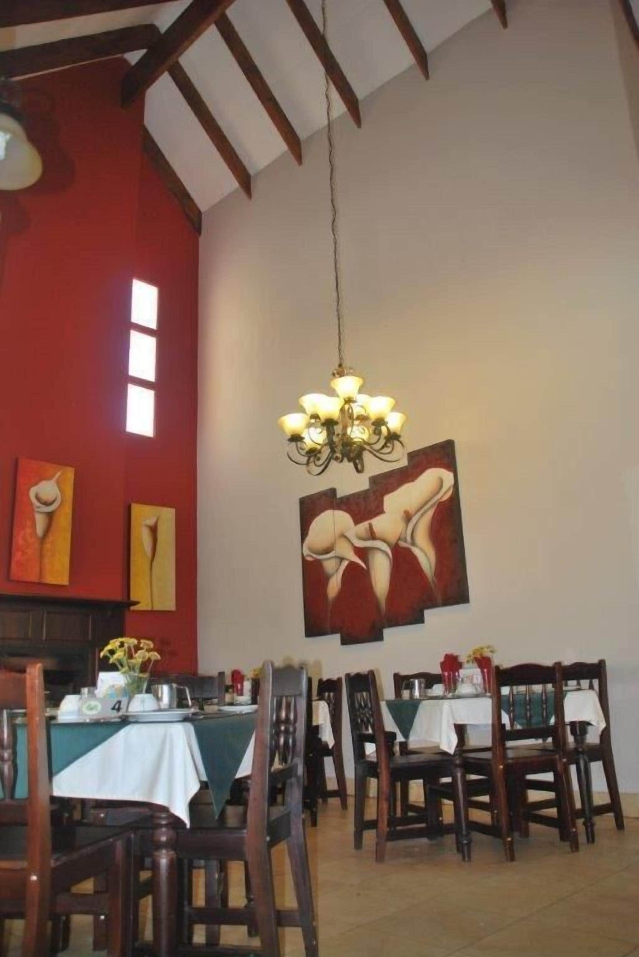 A dining area with wooden chairs and tables, a chandelier, and abstract wall art.