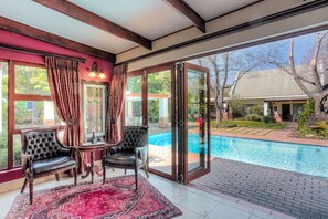A room with a pool view, a red carpet, and a glass door leading outside. - Sunninghill Guest Lodge (Sandton)