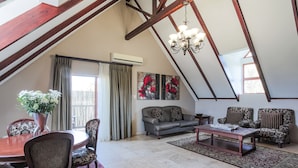 A spacious loft with a dining area, two sofas, a coffee table, and a chandelier. - Sunninghill Guest Lodge (Sandton)