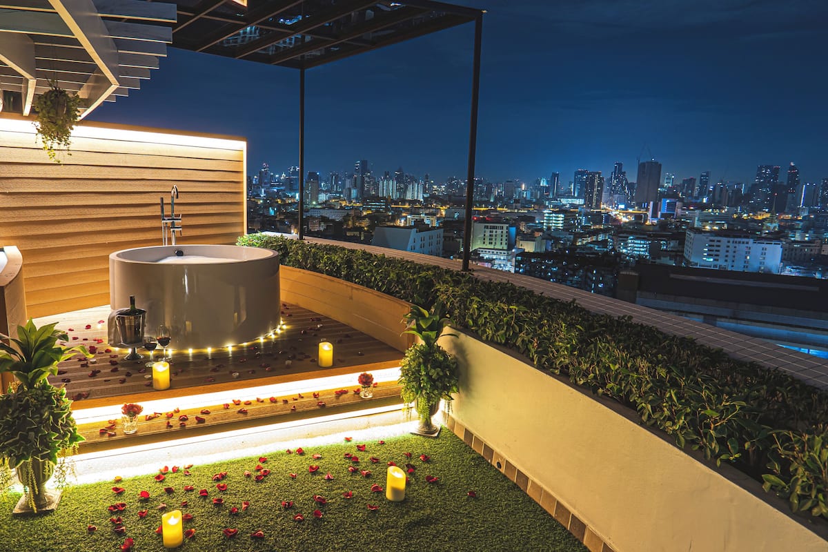 Une terrasse sur le toit avec un jacuzzi, de la verdure et une vue sur la ville.