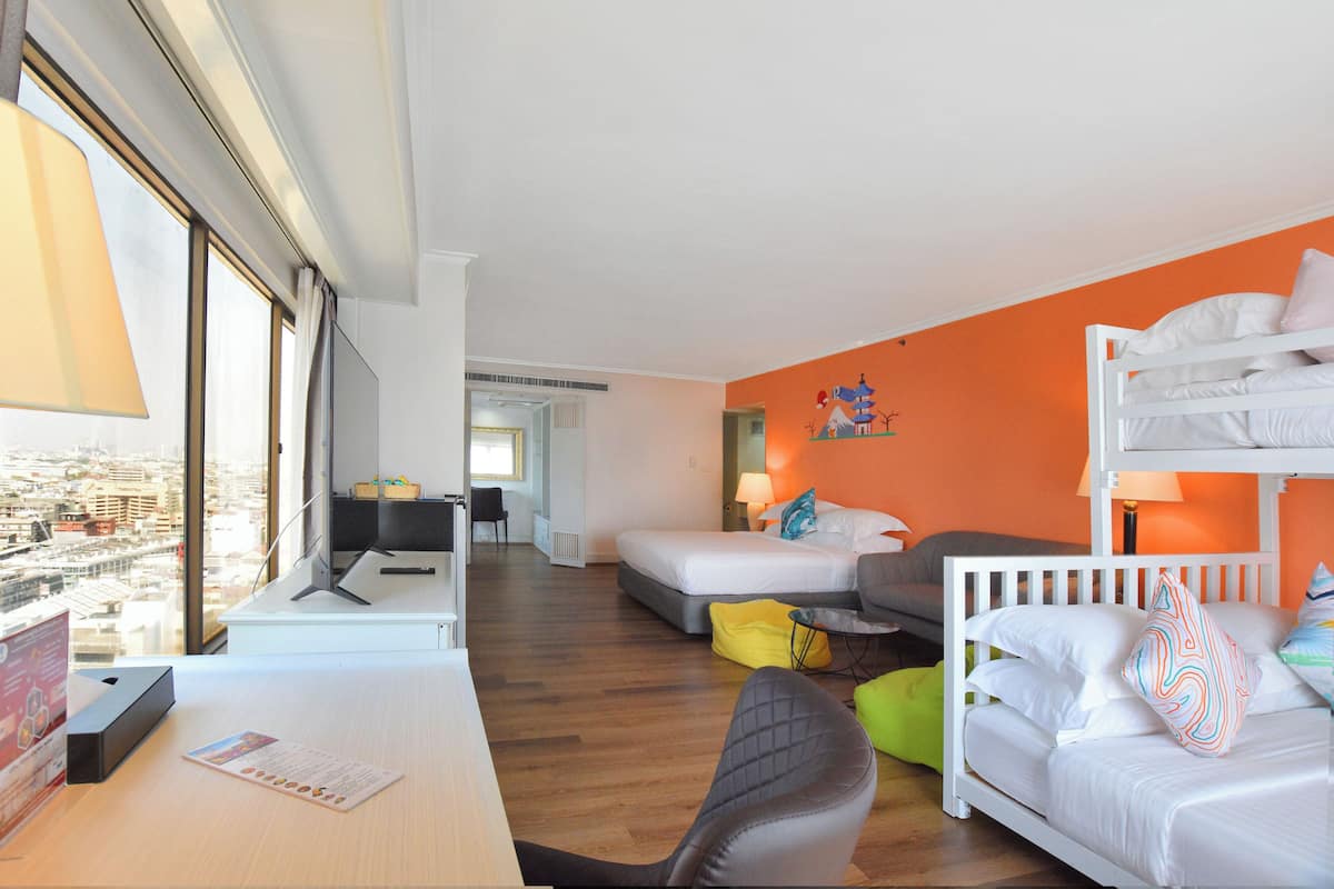 Une chambre d’hôtel équipée d’un bureau, de deux lits, d’un canapé et offrant une vue sur la ville.