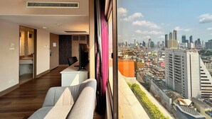 Habitación de hotel moderna con vistas a la ciudad, un escritorio, una silla y un ventanal grande.