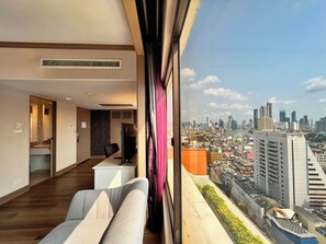 A modern hotel room with a city view, a desk, a chair, and a large window. - Grand China Bangkok (Bangkok)