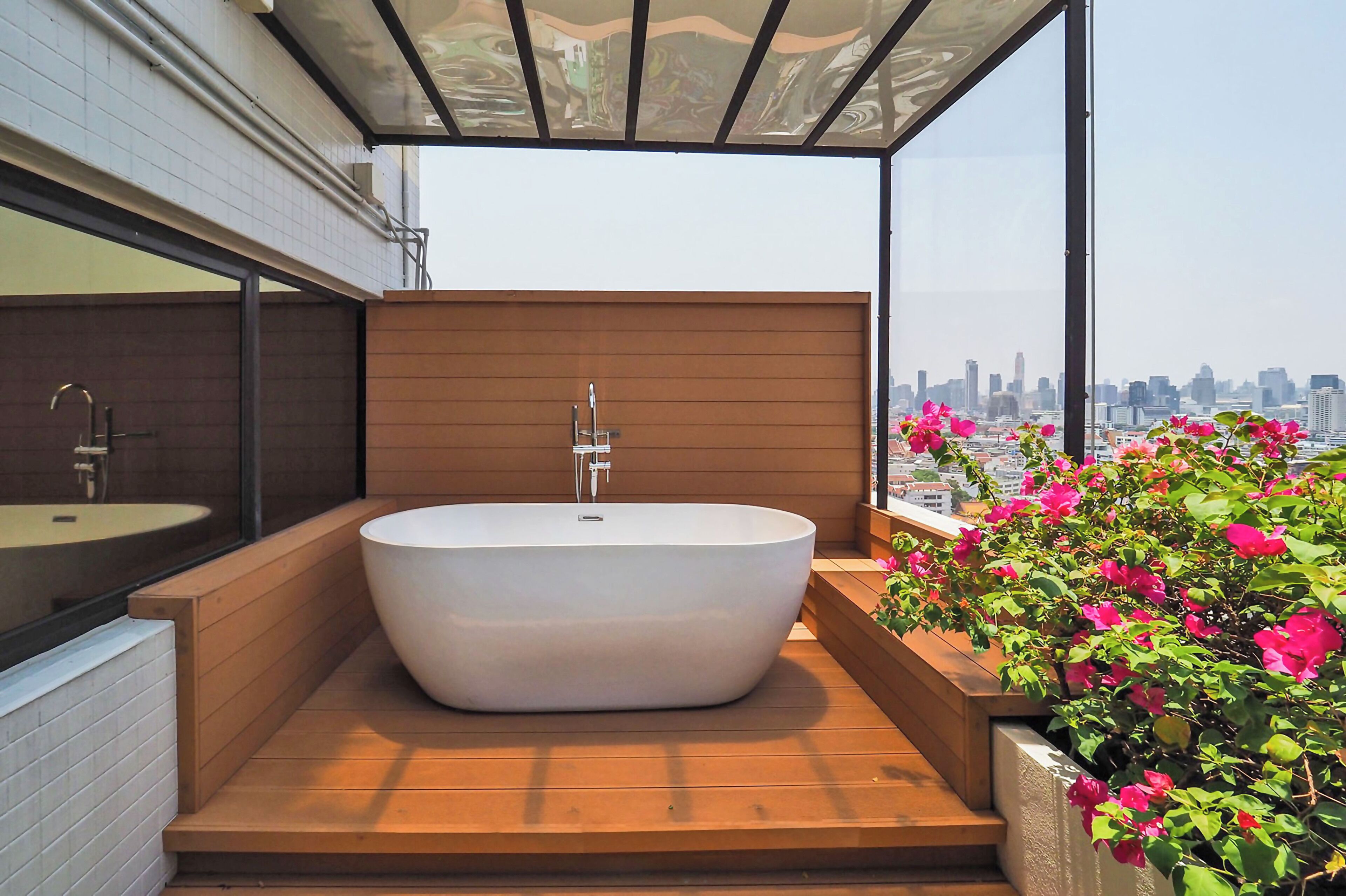 Un baño moderno con una bañera independiente, suelo de madera y vistas a la ciudad.