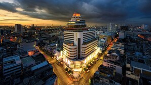 Un hotel moderno con una estructura escalonada distintiva y una gran cúpula central, rodeado por un paisaje urbano al atardecer.
