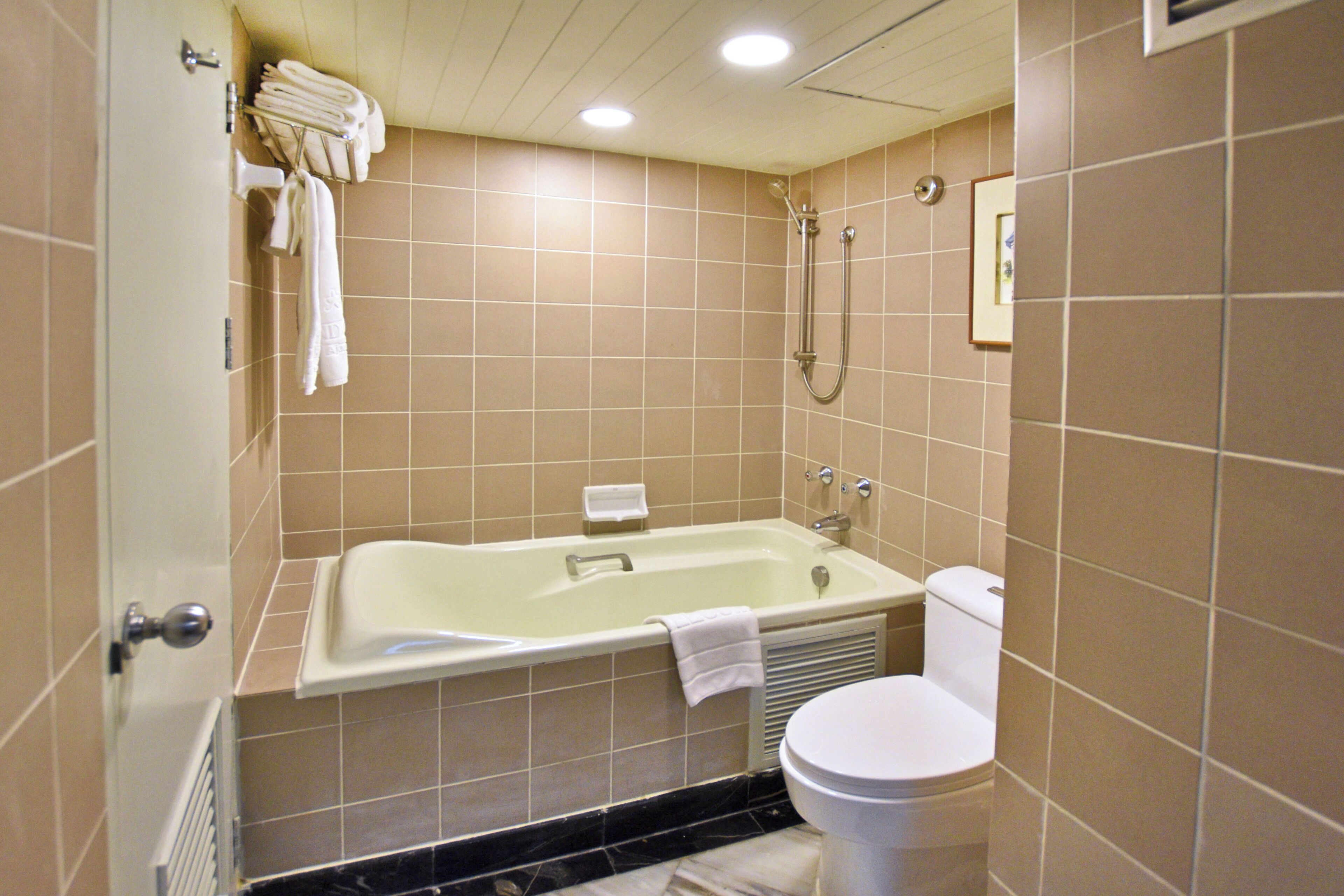 Een badkamer met een bad, toilet en handdoekrek.