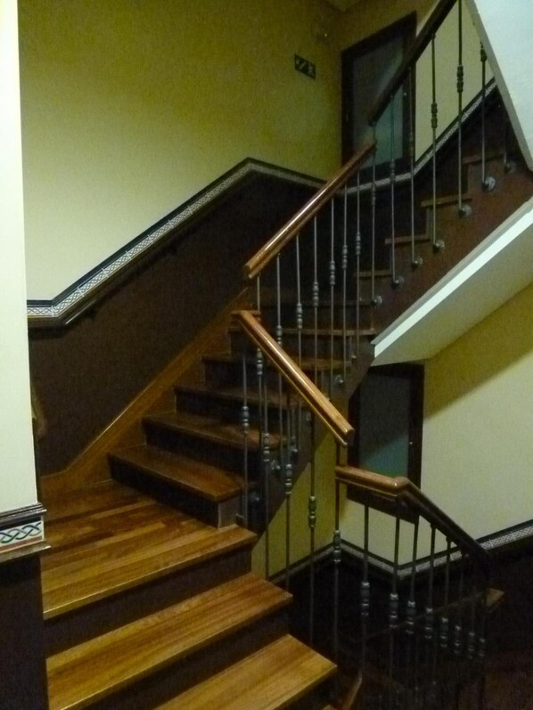 Una escalera de madera con barandales negros y un portón de cristal en la parte superior.
