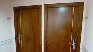 Two wooden doors with a vertical handle, a light switch, and a small electrical outlet on the wall. - Hosteria Sara by gaiarooms (Salamanca)
