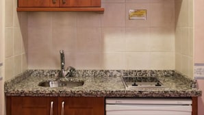 A kitchen with wooden cabinets, a stainless steel range hood, a granite countertop, and a built-in dishwasher. - Hosteria Sara by gaiarooms (Salamanca)