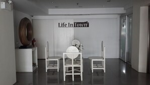 A modern interior with two white chairs, a round table, and a 'Life In Town' sign on the wall. - Life In Town Chiangmai (Chiang Mai)