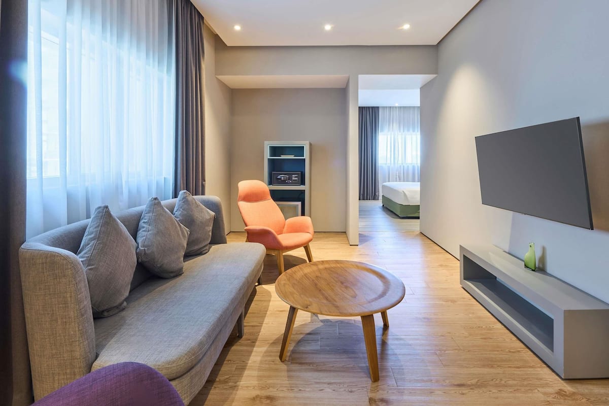 Una sala de estar moderna con sofá, sillón, mesa de centro, televisión y un pequeño mueble para televisión.