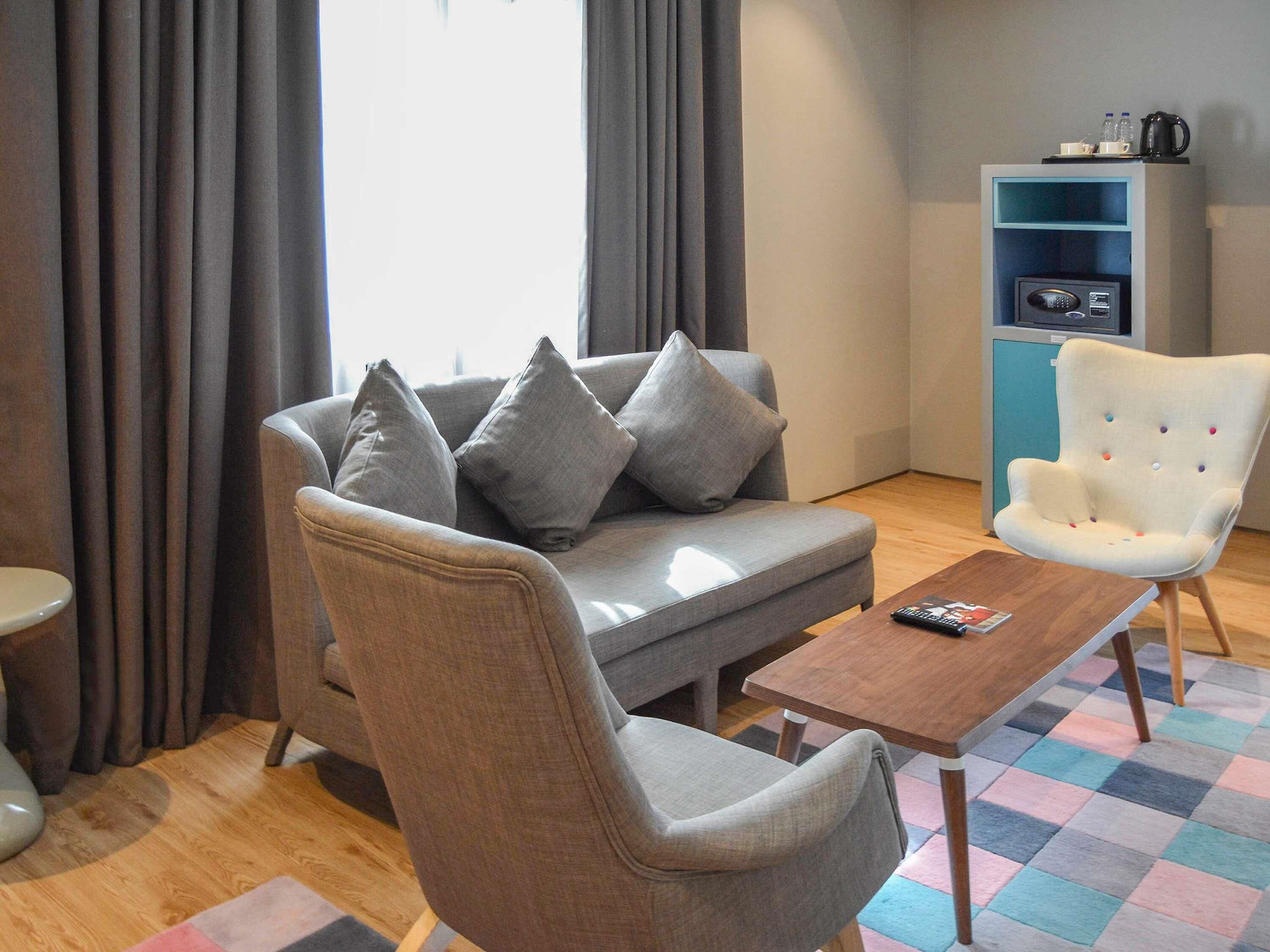 A modern living room with a grey sofa, a white armchair, a wooden coffee table, and a blue shelving unit.