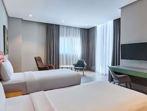 Una habitación de hotel con dos camas, un escritorio, una silla y una televisión.