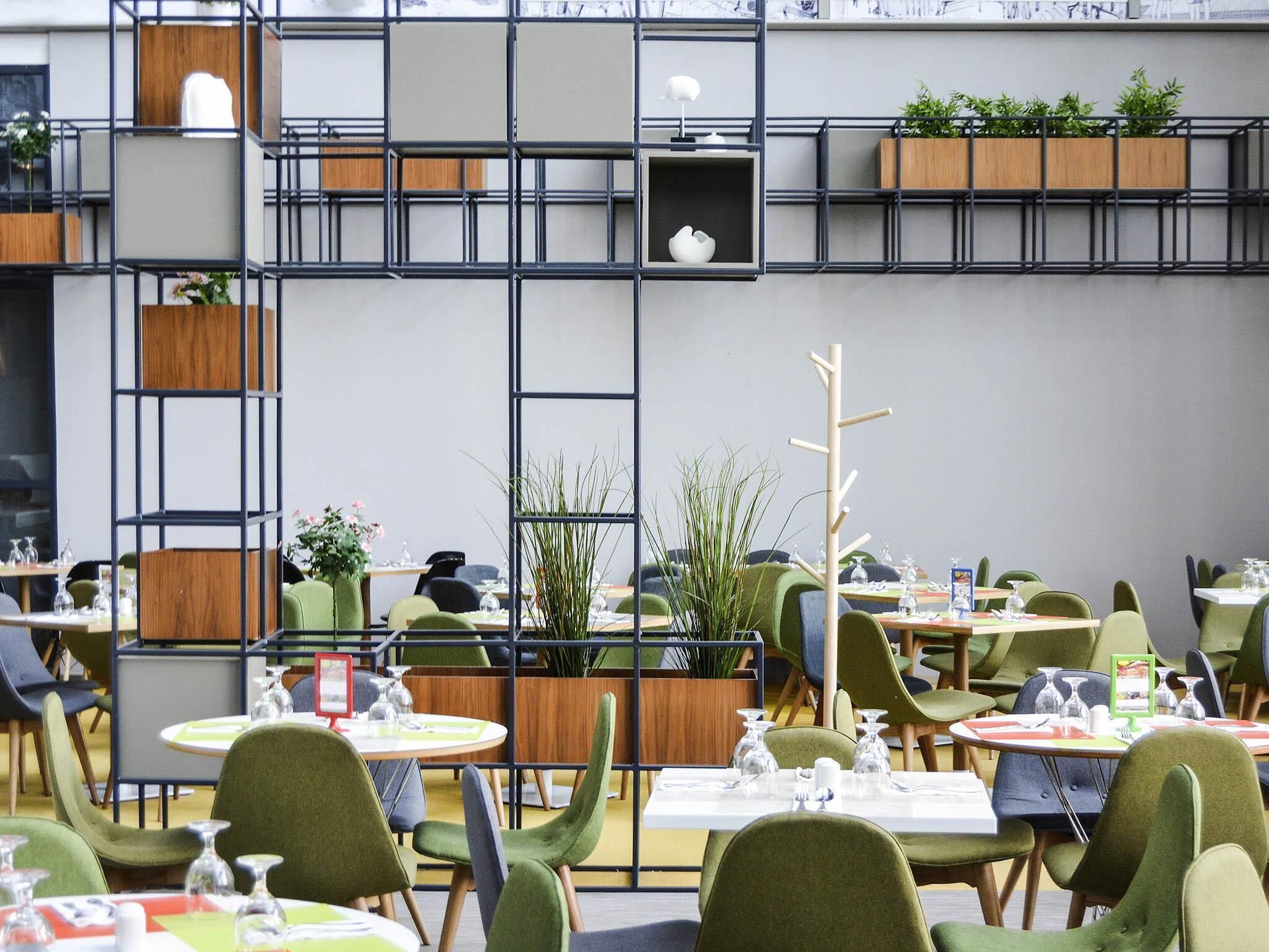 Ein Restaurant mit mehreren Tischen und Stühlen, einige davon mit Pflanzen.