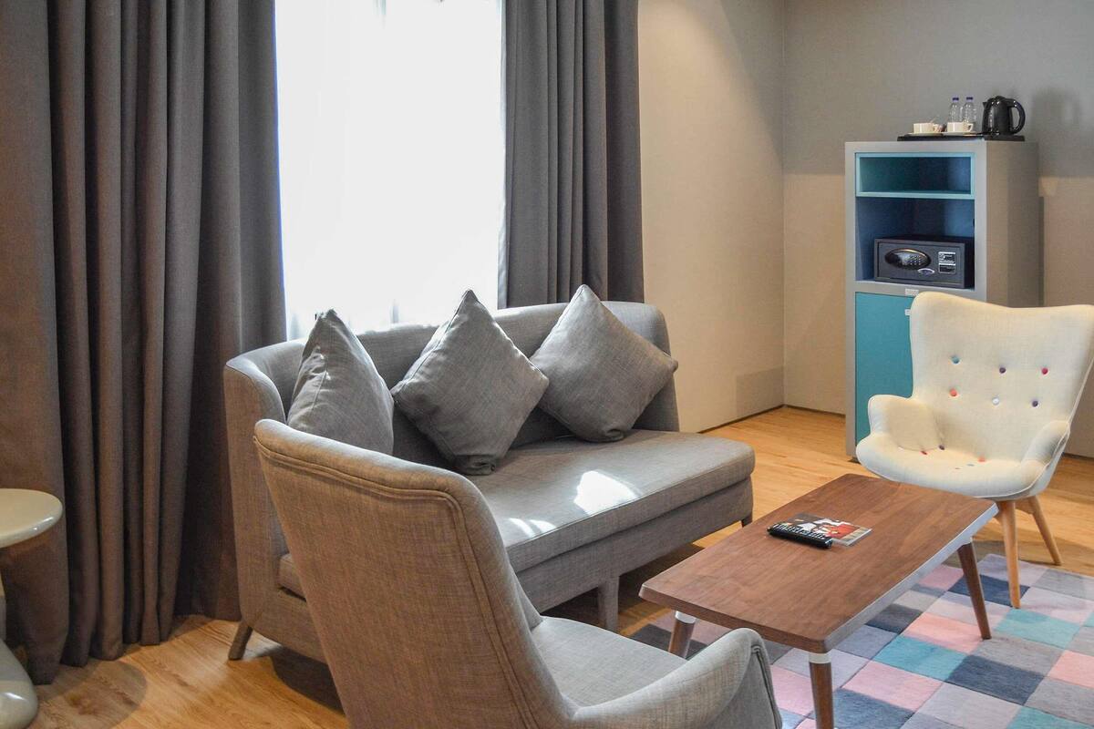 Una sala de estar moderna con un sofá gris, un sillón blanco, una mesa de centro de madera y un estante azul.