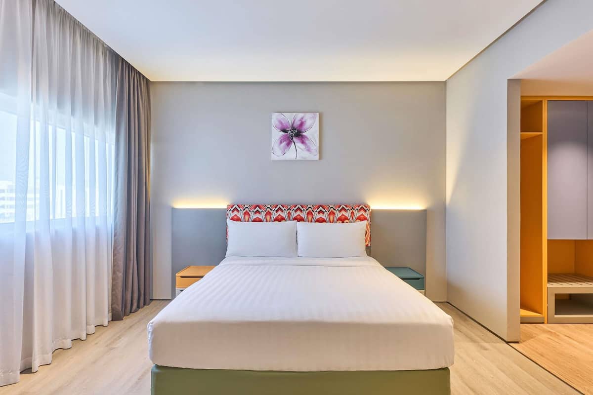 Una habitación de hotel con cama, mesita de noche, una obra de arte en la pared y un armario.
