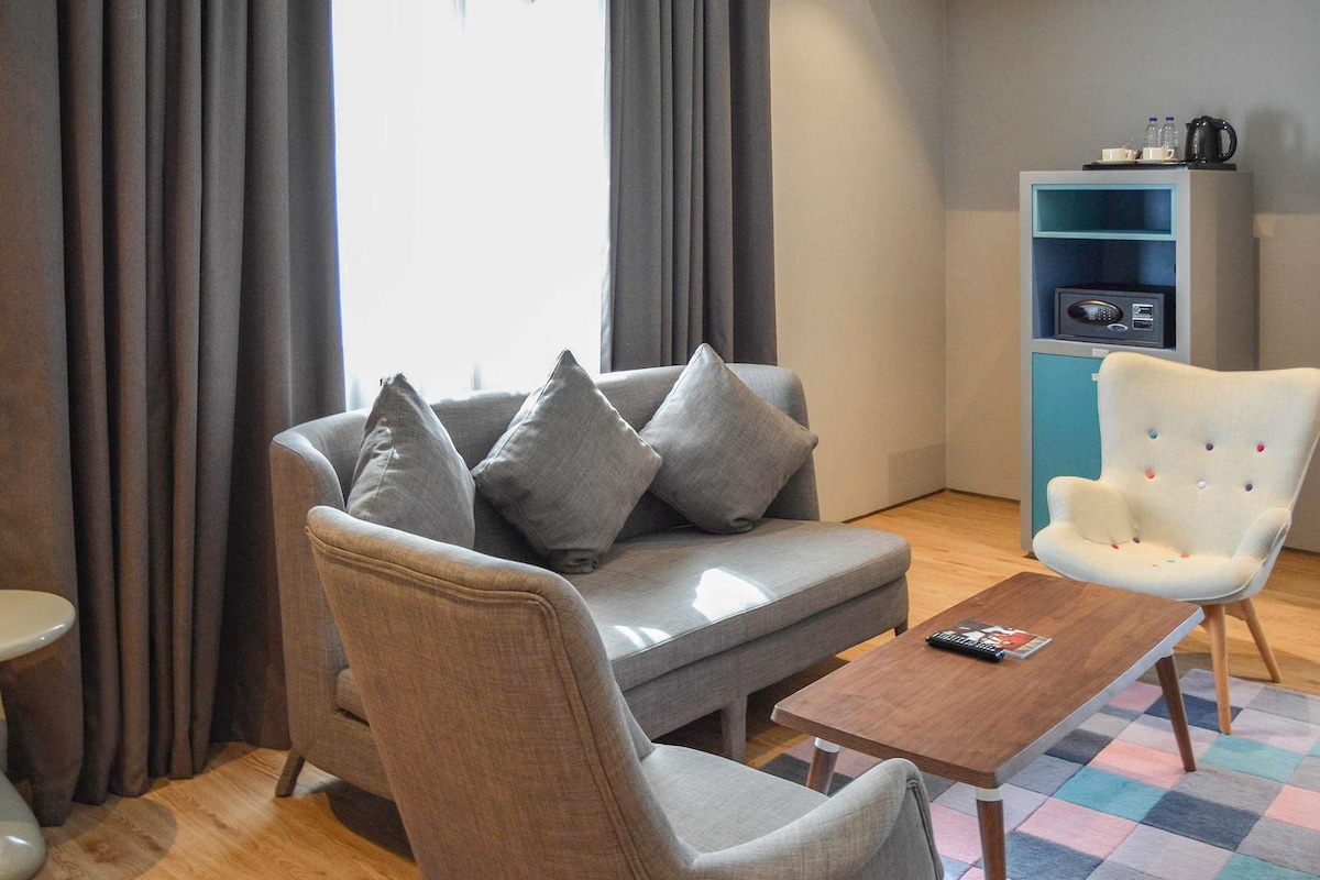 Una sala de estar moderna con un sofá gris, un sillón blanco, una mesa de centro de madera y un estante azul.