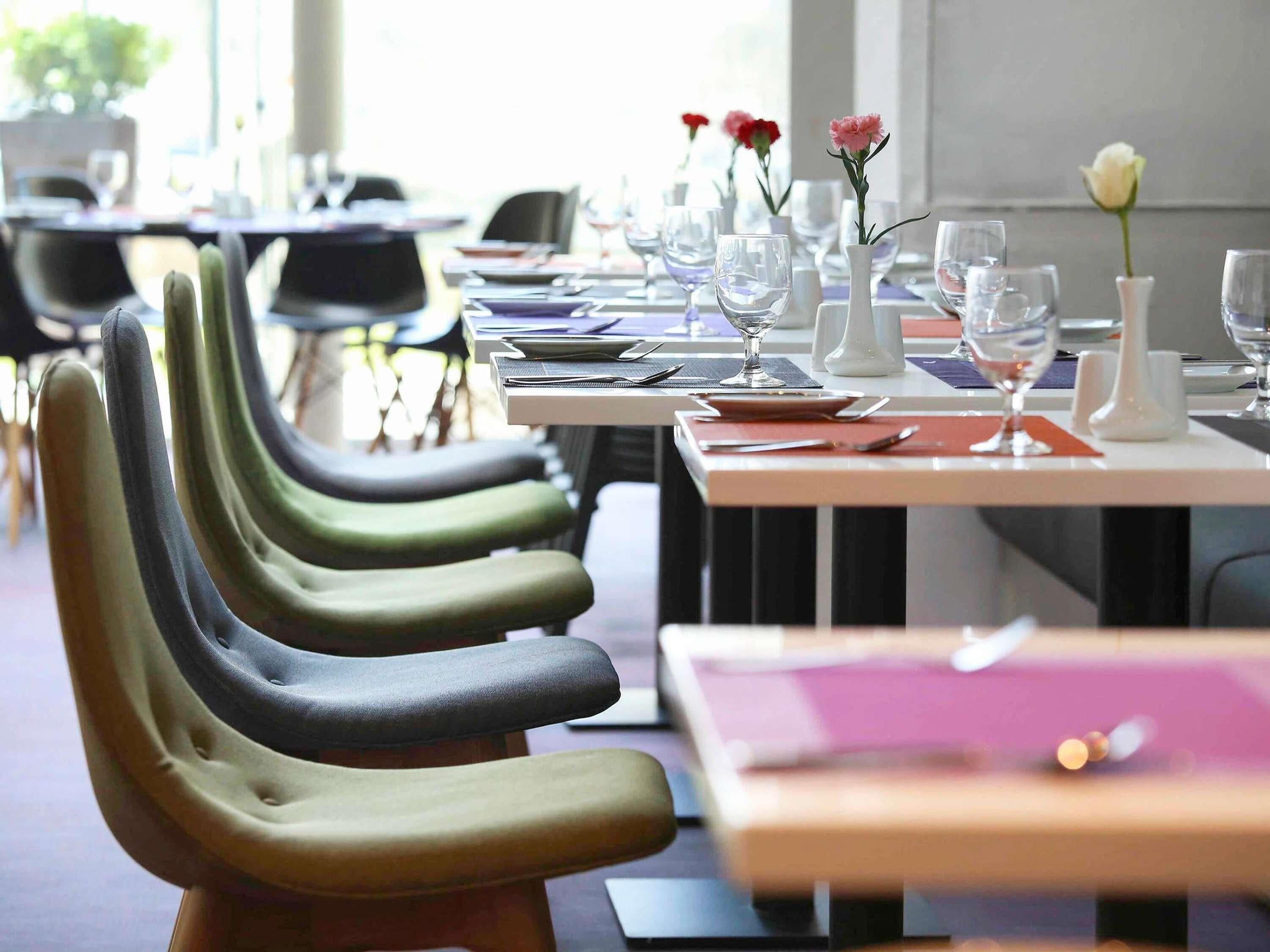 Ein Restaurant mit mehreren Tischen, Stühlen und einer Vase mit Blumen.