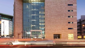 A modern hotel building with a glass facade, a prominent sign reading 'ibis Styles Hotel,' and a parking garage adjacent to it. - ibis Styles Dubai Jumeira (Dubai)