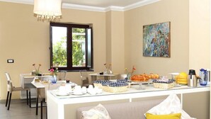 Un espace repas avec un buffet, une fenêtre donnant sur un paysage verdoyant et un tableau accroché au mur.