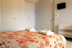 Ett hotellrum med en säng, en tv som är monterad på väggen och en termostat på väggen.