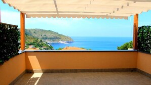 Un balcon avec vue sur la mer et une colline.