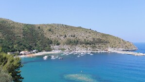 Une zone côtière avec une plage, des bateaux et des bâtiments situés sur le versant d’une colline.