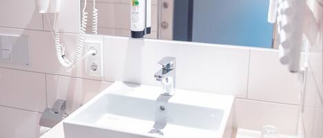 A bathroom with a white sink, a hairdryer, and a towel rack.