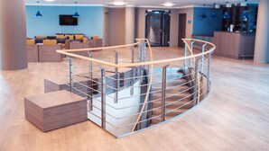 Un moderno vestíbulo de hotel con una escalera curva, zona de estar y un mostrador de recepción.
