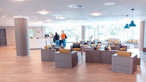 Un vestíbulo amplio con mobiliario moderno, ventanas grandes y una mesa de recepción.
