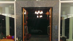 A hotel entrance with a stone facade, a chandelier, and potted plants. - Natee Place (Chiang Mai)