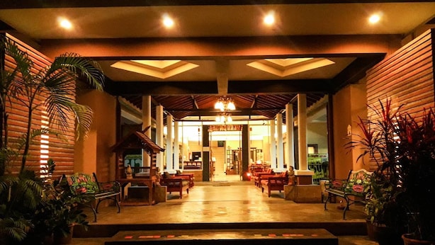 A hotel entrance with a covered walkway, seating area, and potted plants. - Natee Place (Chiang Mai)