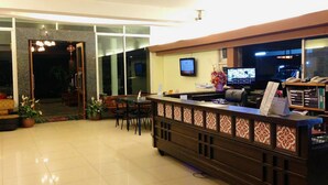 A hotel reception area with a reception desk, chairs, a TV, and a computer monitor. - Natee Place (Chiang Mai)