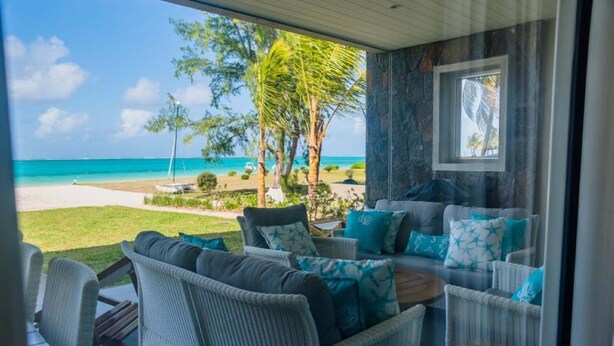 Een balkon met rieten meubilair en uitzicht op het strand.